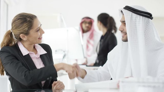  Smiling Western & Arab business people shake hands in meeting
