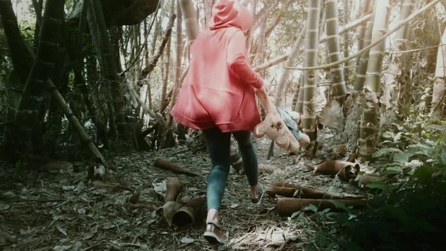 Woman holding her teddy bear runs  through the bamboo jungle in Colombia, Slow motion