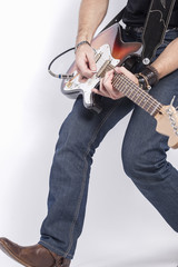 Fototapeta na wymiar Professional Guitar Musician Legs Closeup. Posing Against White