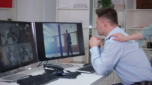  Security worker in system control room gets caught out watching TV on screen.