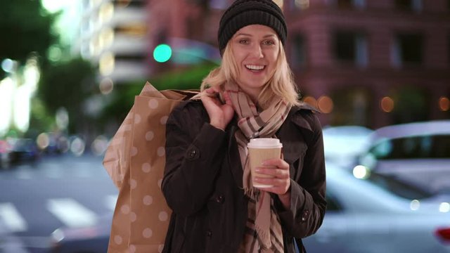 Attractive woman smiling at camera with shopping bags