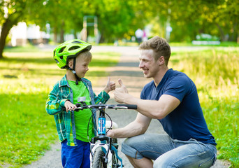 father talking with his son riding a bicycle