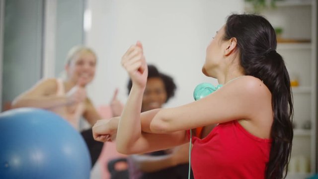  Portrait of smiling woman taking a break & talking to friends in exercise cla