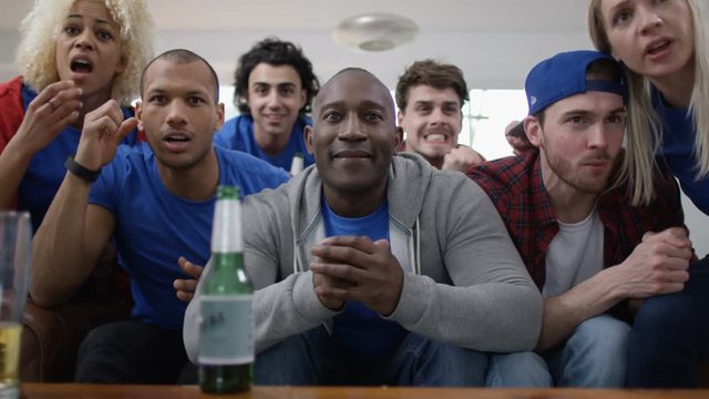  Group of friends watching sports game on TV celebrate when team score
