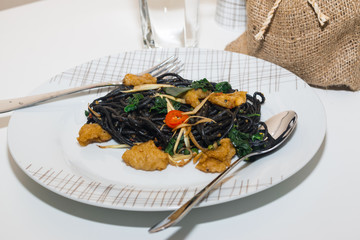 Black spaghetti with prawns on white plate
