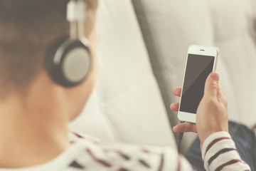 Young man listening to music on smartphone in the room