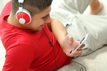 Young man listening to music on smartphone in the room