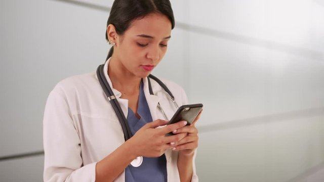Mexican woman doctor texting on smartphone