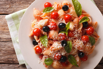 pasta with tomatoes, olives and parmesan cheese close-up. Horizontal top view
