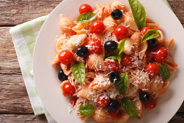pasta with tomatoes, olives and parmesan cheese close-up. Horizontal top view
