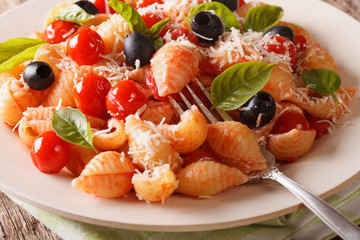 Italian pasta Conchiglie with tomatoes, olives and parmesan close-up. horizontal
