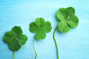 Green four-leaf clovers on wooden background © Africa Studio