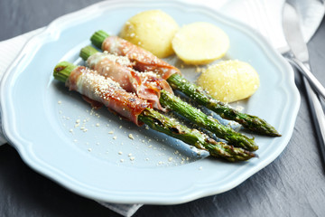 Grilled asparagus with bacon and potatoes on plate