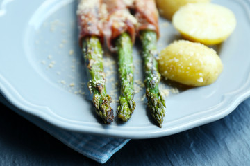 Grilled asparagus with bacon and potatoes on plate