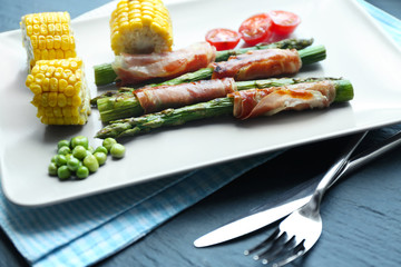 Asparagus with bacon and vegetables on plate