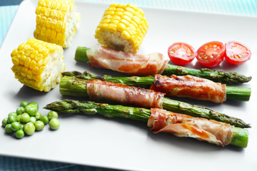 Asparagus with bacon and vegetables on plate
