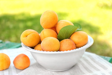 Heap of apricots in white plate on table