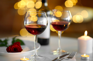 Romantic composition with wine and candle on blurred background