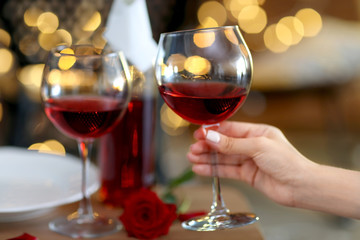 Female hand with glass of wine on blurred background