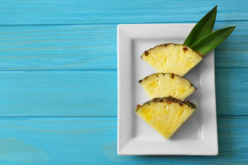 Pineapple slices and leaves in plate on blue background