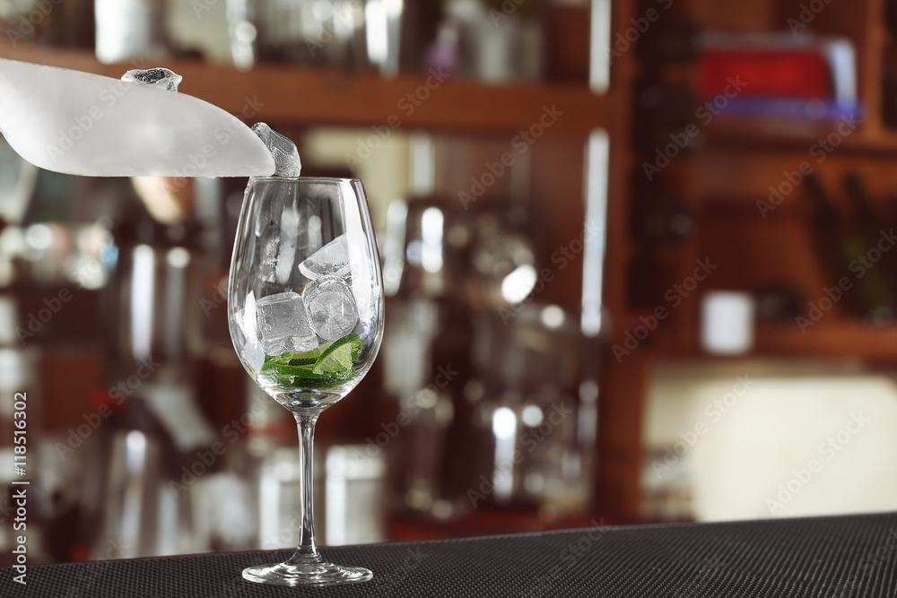 Wall mural woman hands adding ice into cocktail on bar counter