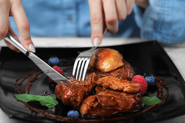 Woman eating juicy meat with sweet sauce in restaurant
