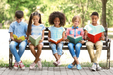 Cute kids reading books on bench - Powered by Adobe