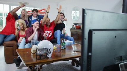 Friends watching American football game on TV celebrate when team scores - Powered by Adobe