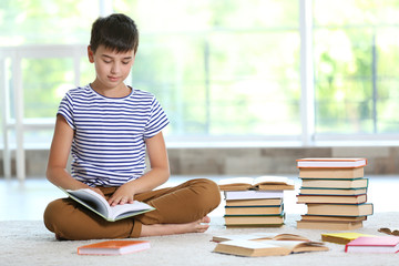 Cute boy reading book at home