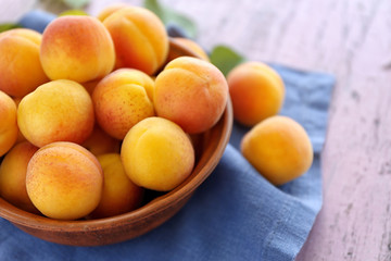 Fresh juicy apricots in bowl on wooden table