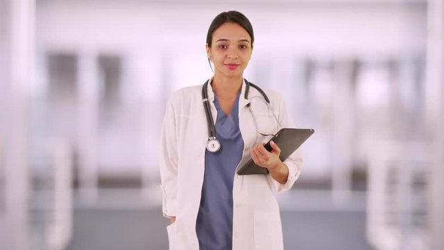 Smiling Mexican woman doctor holding tablet