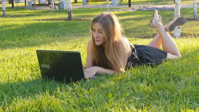Woman on laptop outside on grass