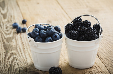 Fresh blueberries and blackberries in decorative ceramic buckets