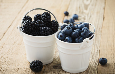 Fresh blueberries and blackberries in decorative ceramic buckets