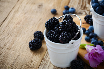 Fresh blueberries and blackberries in decorative ceramic buckets