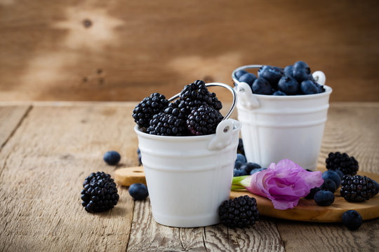 Fresh blueberries and blackberries in decorative ceramic buckets