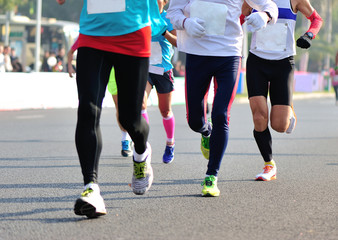 Fototapeta premium Unidentified marathon athletes legs running on city road