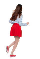 side view of running  woman. beautiful girl in motion. backside view of person.  Rear view people collection. Isolated over white background. Long-haired brunette in red skirt runs diagonally