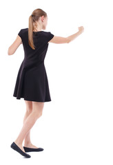 Fototapeta premium skinny woman funny fights waving his arms and legs. Isolated over white background. Blonde in a short black dress boxing
