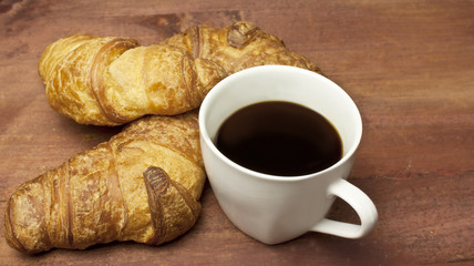 Cup of dark coffee with croissants, on wooden boards