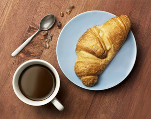 Cup of black coffee with croissant, shot from above