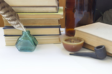 Retro still life with vintage things: old books, pen with ink jar, candle and a smoking pipe.