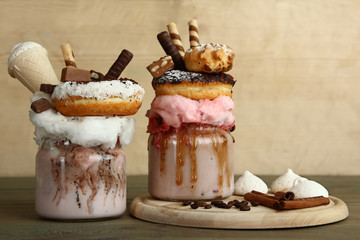 Milkshake, doughnuts and other sweets in a jar on wooden background