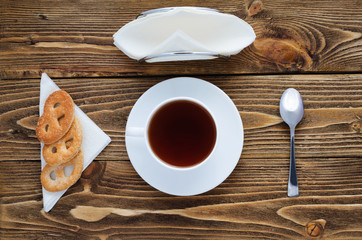 Cup of tea on a wooden table, sugar, spoon, biscuits, napkins, top view