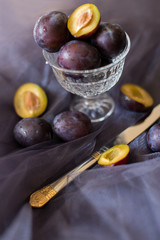 plums on a dark background in a glass vase clay blue summer berry fruits