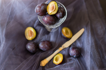 plums on a dark background in a glass vase clay blue summer berry fruits