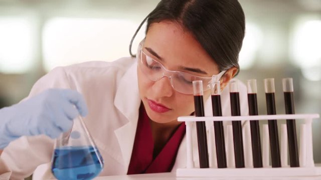 Latino scientist looking at liquids in vials