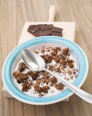 bowl of cereal with milk and chocolate on natural wooden