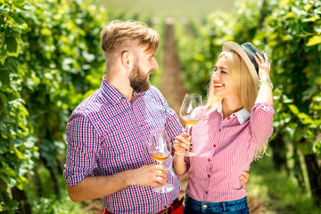 Beautiful caucasian couple in checkered shirts having fun with glasses of wine on the vineyard. Green tourism at the winery