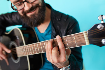 Bearded hipster man hand playing on acoustic guitar.